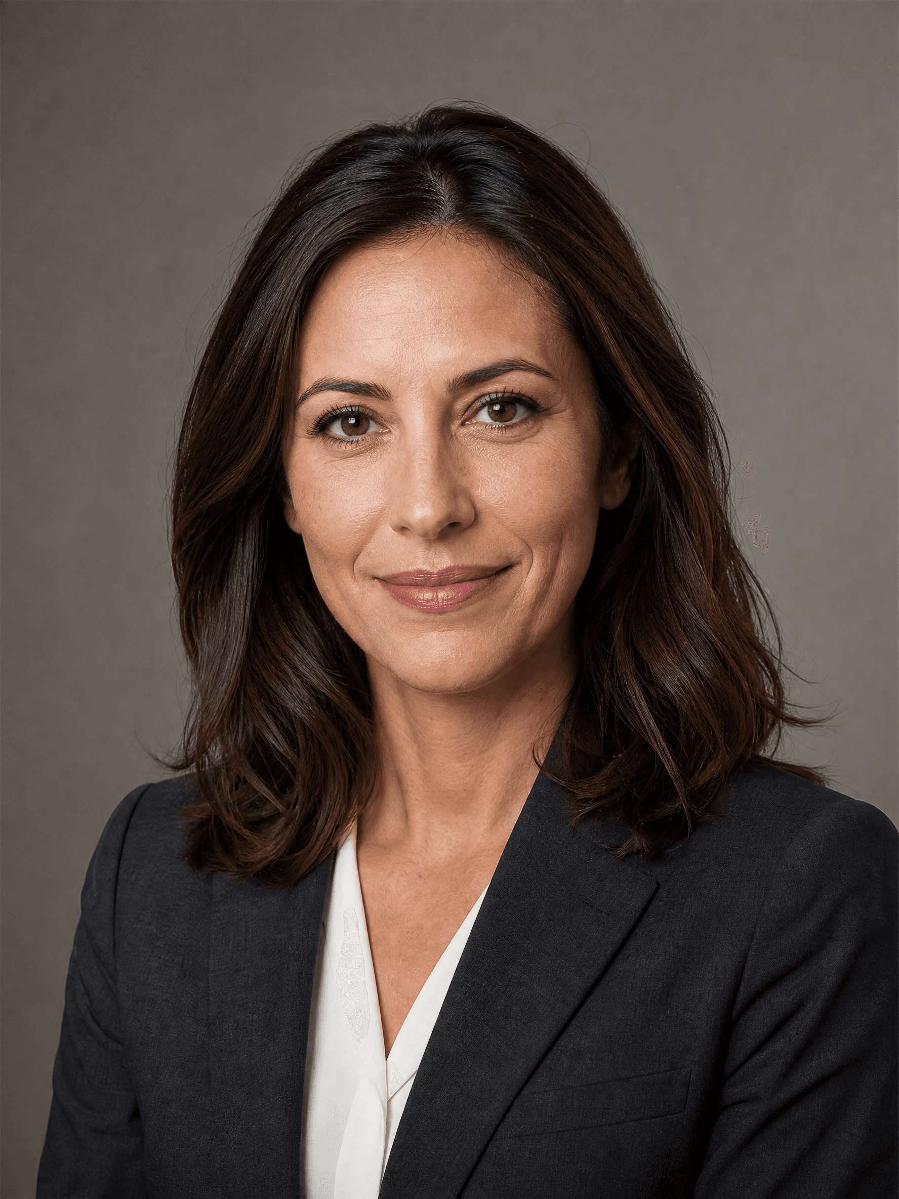 Ritratto professionale di una donna con blazer grigio antracite e camicia bianca su fondo grigio caldo