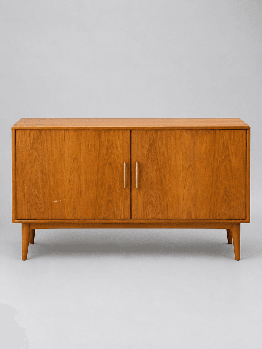 Dasselbe Teak-Sideboard freigestellt vor hellgrauem Hintergrund, Kratzer an der linken Tür weiterhin sichtbar